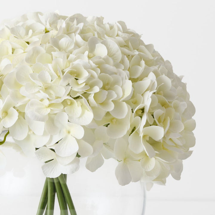 Artificial white hydrangeas in large round glass vase – view 2