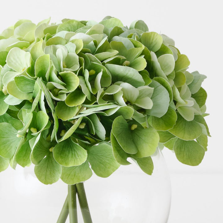 Artificial light green hydrangeas in small round glass vase – view 2