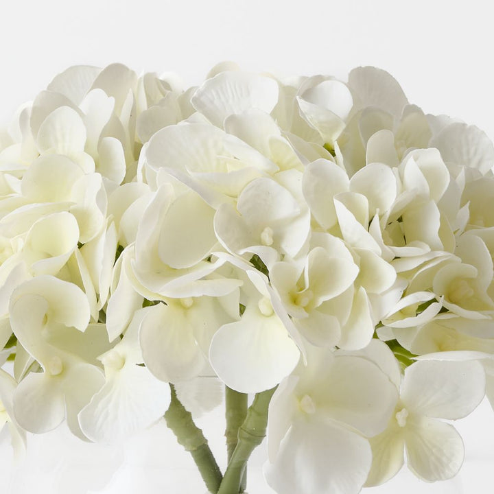 Artificial white hydrangeas in small round glass vase – view 2